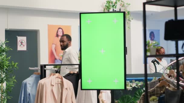 エレガントなフォーマルウェアの新しいコレクションを宣伝する高級衣料品店のグリーンスクリーンキオスク 店舗の衣服を促進するために使用されるファッションブティックのクロマキーモックアップデジタルディスプレイ — ストック動画