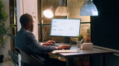 Muhasebeci, gece vardiyasında belgelerin kalite güvencesi beklentilerine ve standartlara uygun olduğundan emin olmak istiyor. Çalışan bilgisayar ekranında evrak detaylarını kontrol ediyor