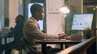 African american employee pissed about noisy coworker listening to music and pretending to beat drums in office. Businessman frustrated with overzealous colleague banging desk