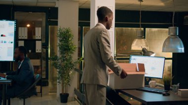 Ayrılmaya karar verdikten sonra modern ofisten ayrılan üzgün bir çalışan. Hüsrana uğramış işadamı, yeni işe başlamadan önce dün gece vardiyası bittikten sonra iş yerinde masa eşyası kutusunu topluyor.