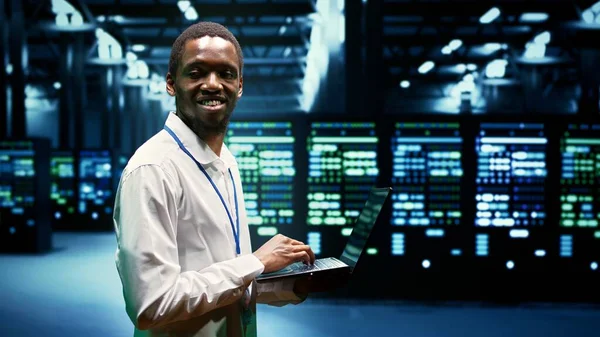 African american engineer inspecting interlinked computers creating server network. High tech facility using parallel computing to perform complex calculations and process large amounts of data