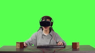 VR oyunlarından hoşlanan oyuncunun POV 'u yeşil ekran arkaplanının üzerinde oturuyor, arkadaşlarıyla web oyunu oynuyor ve RPG oyunlarıyla eğleniyor. Sanal gerçeklik başlığı kullanan adam.