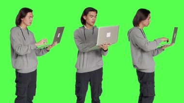 İnternette gezinen modern bir adam yeşil ekran arkaplanının başında duruyor kablosuz bilgisayar kullanarak internet sitesine göz atıyor. Sosyal medyayı kontrol eden ya da iş yapan genç yetişkinler.
