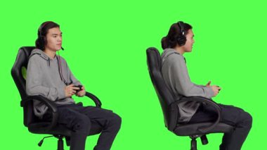 Neşeli insan stüdyoda video oyunları oynuyor, arkadaşlarıyla izole edilmiş yeşil perde arkaplanına karşı online oyun araştırmasında eğleniyor. Ofis sandalyesinde otururken Asyalı adam oyunu, roket oyunu.