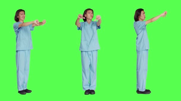 アジアの看護師はスタジオで親指を下げ 全身の緑色の背景に嫌悪感とネガティブなシンボルを示しています 不満や不承認を表明する不満の医療アシスタント — ストック動画