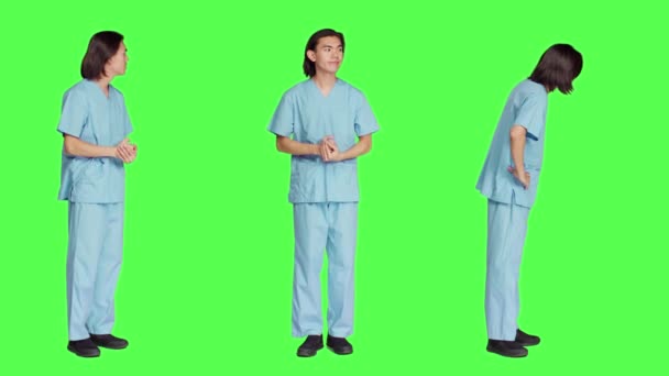 緑色の壁の上に 医療従事者はイベントを待って 病院の防護服を着て心配している 医学の専門知識と自然能力を持つ男はスタジオに立っています — ストック動画