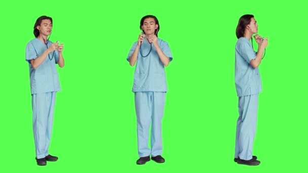 専門の制服を装備し 病院で診察を受ける準備をしている フルボディグリーンバックドロップに対抗する器具を使用したアジアの看護師 — ストック動画