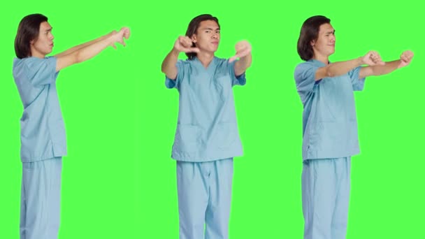 スタジオで親指を示すアジアの専門家は 緑色の背景に嫌悪とネガティブなジェスチャーを与えます 不満を表明する不満の医療看護師 不承認 — ストック動画