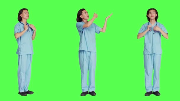 医療業界で働いている男性専門家は フルボディグリーンスクリーンの背景に対して広告コマーシャルを行っています 青い制服の医学は マーケティング広告を提示する左側または右側を指します — ストック動画