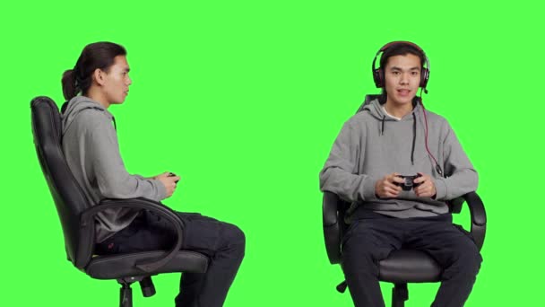 Asian Man Using Joystick Gameplay Sitting Chair Greenscreen Backdrop Studio — Stock Video