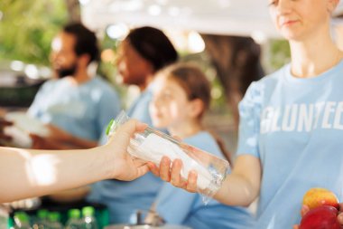 Young volunteers compassionately distribute food boxes, providing assistance to the poor. Detailed image of female charity worker giving water and fresh fruits to the needy, less fortunate individual. clipart