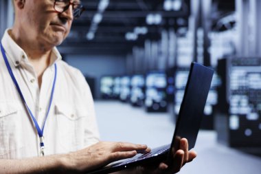 Güç dalgalanmaları için sunucu satırlarını incelemek için dizüstü bilgisayar kullanan Senescent sistem yöneticisi. Veri merkezi birimlerini izleyen, potansiyel kusurları belirleyen bilgili bir uzman