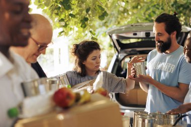 Group of volunteers including African American and Caucasian individuals distribute donated food to homeless and needy. Charity workers support hunger relief and provide essential aid to community. clipart