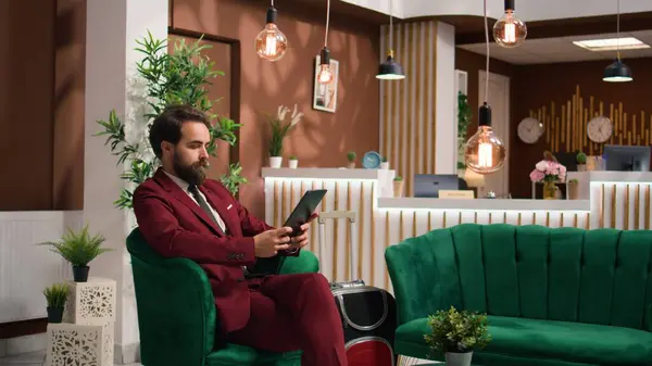 Business associate reads files on tablet to kill time before starting official meeting, lounge area. Entrepreneur preparing speech notes for executive board presentation, travelling for work.