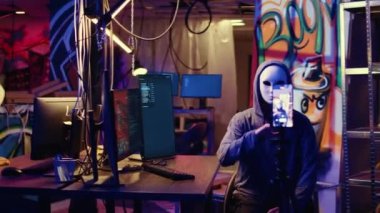 Korsanlar gizli yeraltı üssünde fidye videolarını gizliyor, ödeme talepleri karşılanmazsa çalınan verileri halka açıklamakla tehdit ediyorlar, şantaj görüntülerini kaydetmek için telefon kullanıyorlar.