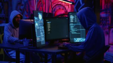 Afrikalı Amerikalı hacker ve Asyalı meslektaşı gizli bir yerde grafiti duvarlarıyla birlikte çalışıyor, güvensiz bilgisayarlara zararlı yazılımlar yerleştiriyor ve haberi olmayan kullanıcılardan hassas verileri çalıyorlar.