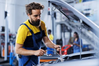 Tamir atölyesinde eski şanzıman yağını yenisiyle değiştirmek için sertifikalı mühendis kullanıyor. Garaj işçisi profesyonel ekipmanla araba bakımı yapıyor.