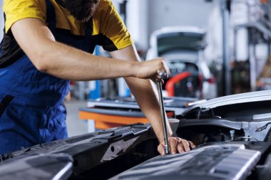 Araba servisindeki tamirci bozuk alternatörü tamir etmek için profesyonel mekanik alet kullanıyor. Garajda uzman bir işçi müşterinin otomobilini tamir ediyor, optimal otomotiv performansını sağlıyor, kapatılıyor