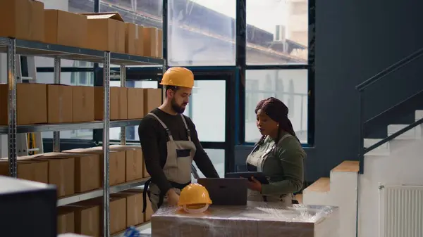 stock image Dolly out shot of employees fulfilling warehouse inventory checkup, keeping quality standards high. Experts in storage room checking labels on cached retail stock, crosschecking delivery info