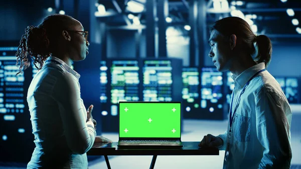 stock image Teamworking professionals running code on chroma key laptop, troubleshooting data center equipment. Tech support executives using green screen device to monitor servers and networking systems