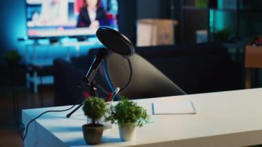 Boş ev stüdyosunun içinde, içinde mikrofon ve mini ev bitkileri olan bir sehpa görüntüsü. RGB ışıklarıyla aydınlatılan dairede podcast kayıt ekipmanları, kapatın
