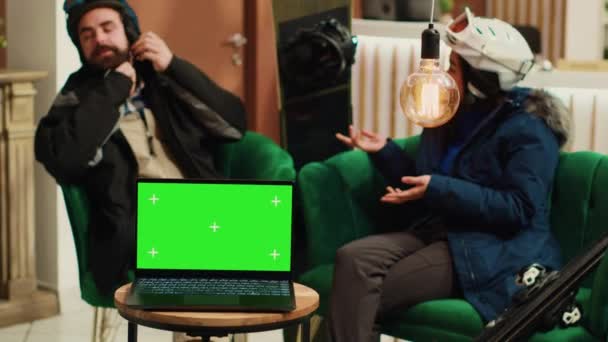 Turyści Stroju Zimowym Salonie Siedzi Laptopem Izolowanym Wyświetlaczem Zielonym Prezentując — Wideo stockowe