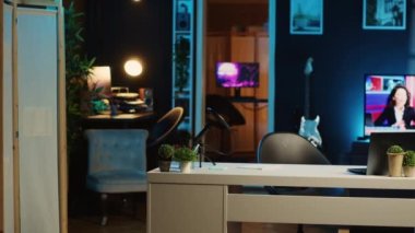Profesyonel mikrofon ve loş ışıklandırılmış ev stüdyosunun içindeki mini ev bitkileriyle çalışma masasının görüntüsü. Oturma odasında RGB ışıklarıyla aydınlatılmış yayın kayıt teknolojisi