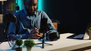 Teknik içerik yaratıcısı, yeni piyasaya çıkan VR gözlüklerini ev stüdyosundaki izleyiciler için kaydediyor. BIPOC etkileyicisi abonelere sanal gerçeklik kulaklığı gösteriyor