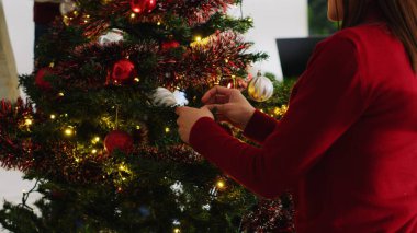 Gizli Noel partisi sırasında çalışanların Noel ağacını çelenklerle, xmas ışıklarıyla ve takılarla süslediği yakın çekim. Personel üyeleri işte birlikte vakit geçiriyorlar, şenlik ruhunun tadını çıkarıyorlar.