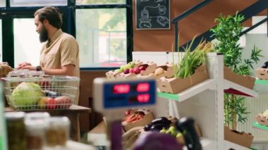 Sıfır atık süpermarketteki adam sağlıklı yiyecek ve kiler arıyor, yerel organik bakkaldan alışveriş yapıyor. Çevre dostu dükkandaki müşteri taze meyve ve sebze arıyor..