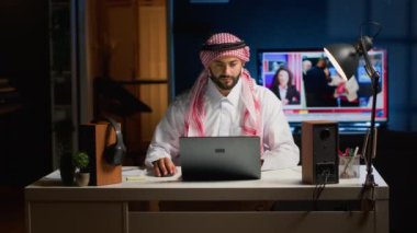 Arap işadamı dizüstü bilgisayarda yazıyor, evde otururken internette geziniyor. Mesleki iş ortamında e-posta yoluyla konuşan Müslüman bir adam, çeşitli görevleri çözmeye odaklandı