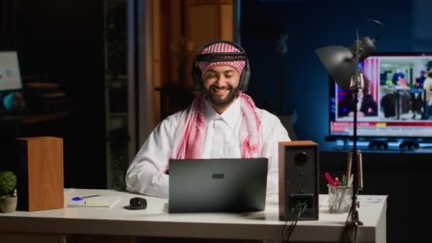 Arabischer Angestellter Mit Drahtlosen Kopfhörern Der Begeistert Vom Fernsehen Auf — Stockvideo