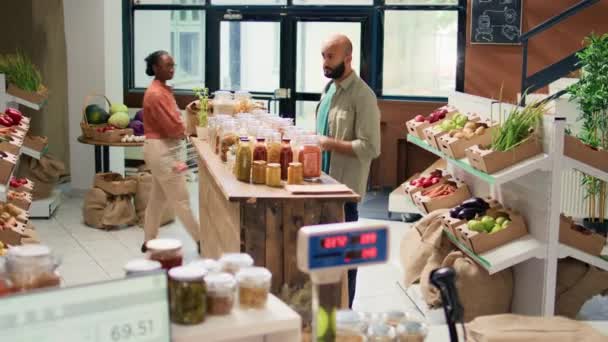 ショップオーナーは クライアントにパスタの種類を示し 天然バイオ食料品店のバルクアイテムでいっぱいの再利用可能な容器を開きます 有機添加物フリー食品を推奨するベンダー — ストック動画