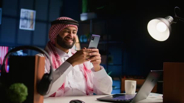 Fröhlicher Arabischer Mann Hause Wohnzimmer Der Nachrichten Auf Dem Smartphone — Stockvideo