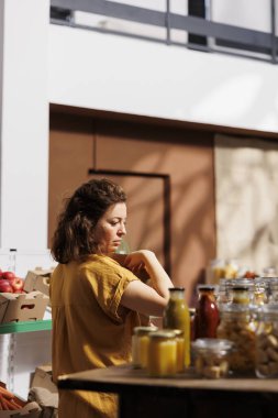Alışveriş yapan kişi dikkatli bir şekilde alıyor, sıfır atık mağazasından biyolojik ürün topluyor, plastik kullanımı en aza indirmek için yeniden kullanılabilir kağıt torbalar kullanıyor. Vejetaryen kiler zımbası arayan yeşil yaşayan bir müşteri.