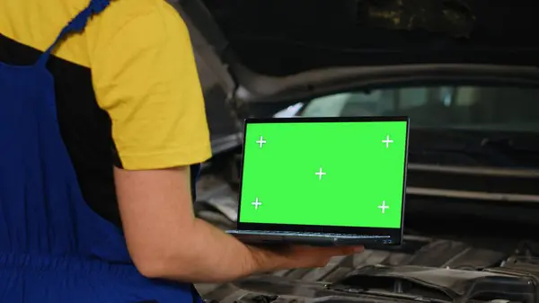 Certified mechanic using mockup laptop in car service to order new parts for damaged vehicle. Close up shot of specialist using device with isolated screen to look online for replacing components