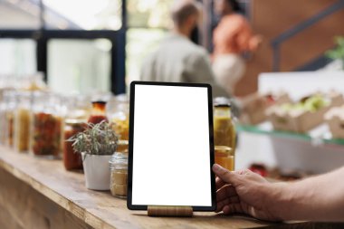 Boş kromakey model şablonu gösteren elektronik tabletin yakın plan görüntüsü. Çevre dostu biyo-gıda deposunda izole edilmiş beyaz bir ekranı gösteren dijital cihazın ayrıntılı görüntüsü.