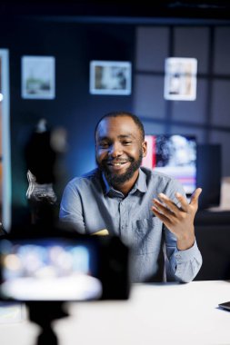 Canlı yayın yapmak ve hayranlarla konuşmak için profesyonel kayıt kamerası ve mikrofon kullanan gülümseyen içerik yaratıcısı. Üyelerine canlı yayın yapmak için video prodüksiyon teçhizatı kullanıyor.