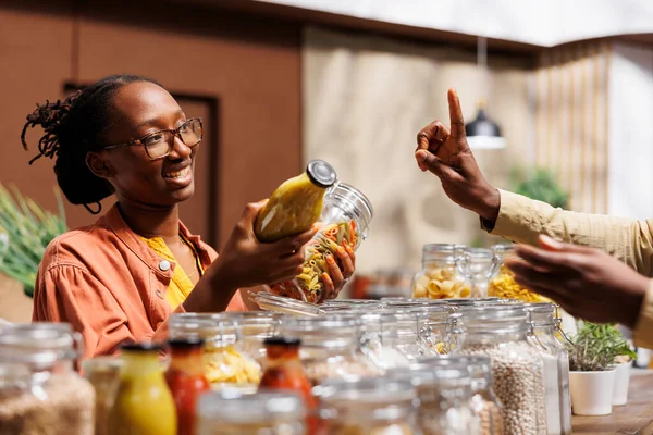 在商店 一个非洲裔美国人卖家提供有机的 当地生产的食物 店主向女顾客提供新鲜蔬菜和没有塑料的食品 — 图库照片