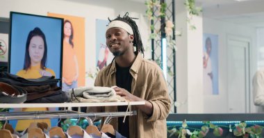 Lüks butik şık kıyafetleri raflarda gezen müşterilerin portresi. Afro-Amerikan müşteri moda giyim mağazasından üst sınıf erkek gömlekleri ve diğer giysiler alıyor.