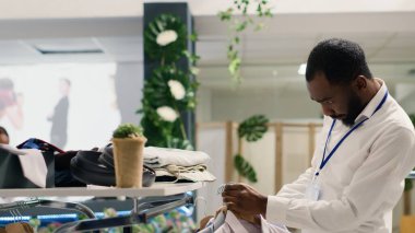 Son trendleri takip ederek alışveriş merkezindeki giyim mağazasında hızlı moda kıyafetleri ayarlayan zarif bir işçi. Moda butiğinde şık erkek ceketlerinin çeşitli organizasyonlarını yapan titiz bir esnaf.