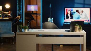 Profesyonel mikrofon ve loş ışıklandırılmış ev stüdyosunun içindeki mini ev bitkileriyle çalışma masasının görüntüsü. Oturma odasında RGB ışıklarıyla aydınlatılmış yayın kayıt teknolojisi