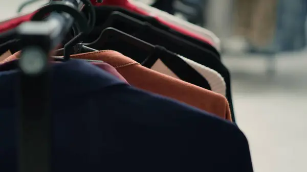 Empty premium fashion boutique with elegant clothes on racks, close up shot. High street men blazers and other garments on hangers in trendy clothing store in shopping center