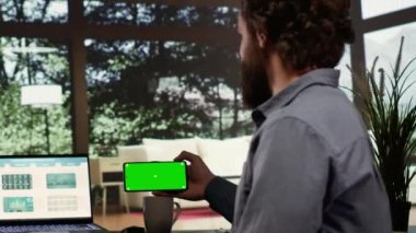 Zengin yatırımcı yeşil ekranı mobil cihazlar üzerinde kullanıyor, ormandaki lüks dağ köşkünden küresel iş geliştirmeye çalışıyor. Telif alanı görüntüsü olan zengin girişimci telefonu tutuyor.