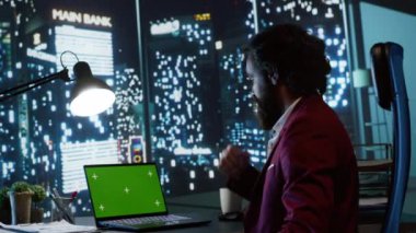 Yasal yatırımcı panoramik görünüm ofisinden izole edilmiş kromaanahtar görüntüsünü inceleyerek, iş istasyonunda yeşil ekranla çalışıyor. Baş yönetici, geceleri kopyalanmış uzay şablonuyla çalışıyor.