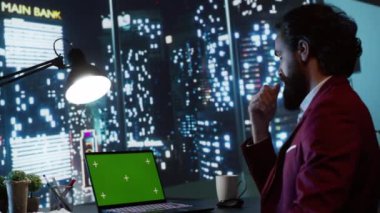 Zengin iş adamı ofis masasından şehir merkezi manzarasına hayran olarak yeşil ekranı laptopta inceliyor. Çalışma saatleri dışında boş telif alanı modelleme şablonuyla çalışan profesyonel yönetici..