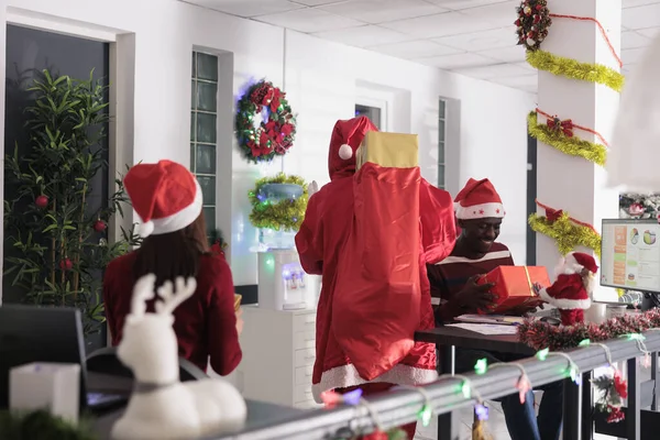 圣诞佳节期间 快乐的圣诞老人给同事们带来了惊喜 身着圣诞服装的同事们在喜庆的装饰办公室里送给那些面带微笑的同事们礼物 — 图库照片
