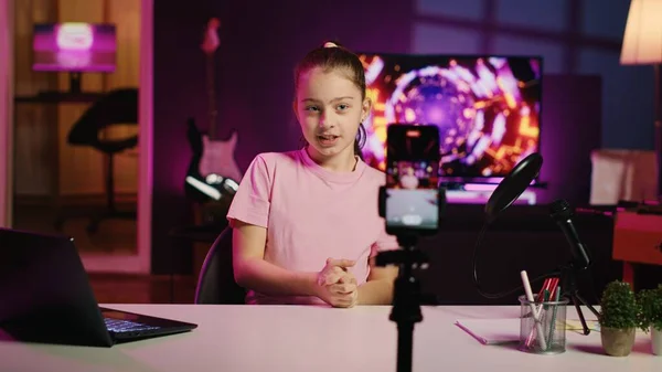 stock image Happy child filming reaction video for gen Z viewers, preparing to look at online videos on laptop, handheld camera shot. Small girl recording reaction to internet clips for social media channels