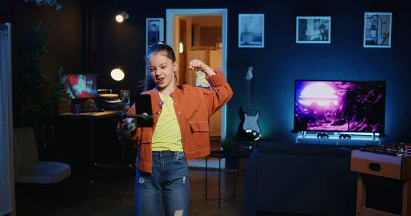 Smartphone on selfie stick used by talented gen z kid in dark room doing viral dance choreography, creating content to generate views and engagement from other online children