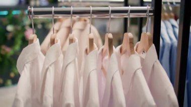 Premium giyim mağazasında yüksek kaliteli kıyafetlerin yakın çekimi. Yeni açılan lüks moda butiğinin içinde beyaz gömlekler giyip müşterileri bekleyen şık bir elbise.